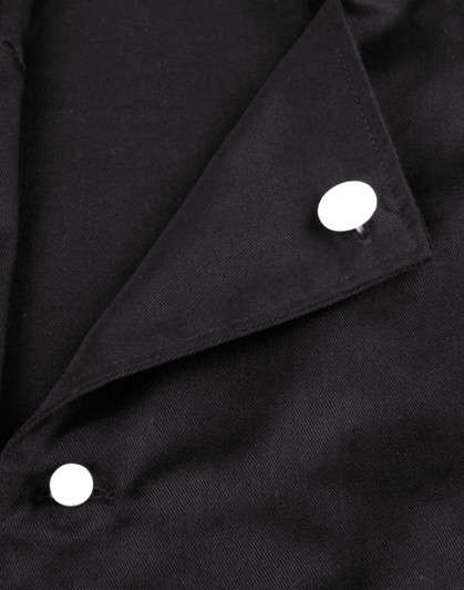 A close-up of a black chef jacket featuring two white exchangeable buttons on the collar.
