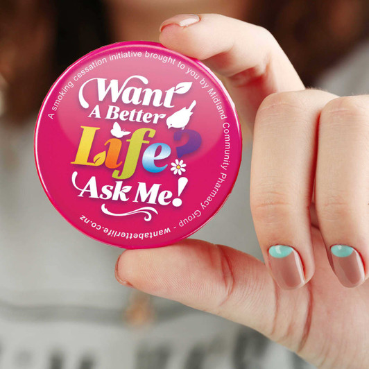 A round, pink button badge with a logo and colourful text on a white background.