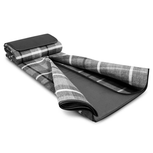A black and grey checkered picnic blanket rolled partially open, featuring a solid black underside and a branding logo.