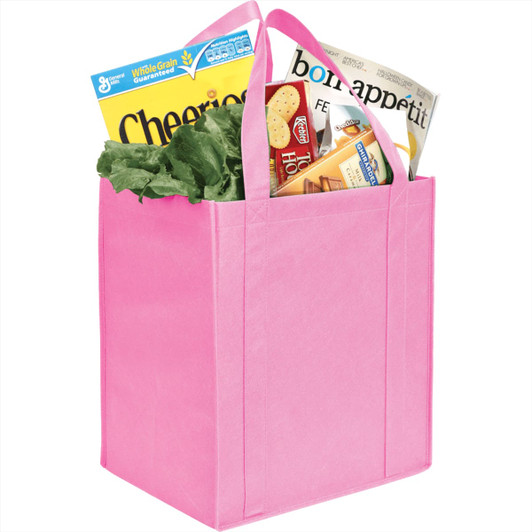 A pink non-woven grocery tote with lettuce, cereal, and a magazine inside. It features sturdy handles and a logo.