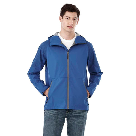 A blue softshell jacket featuring a hood, zip closure, and front pockets, modelled by a man. It has branding on it.