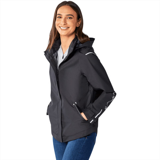 A women's softshell jacket in black, featuring a hood and reflective detailing, alongside a smiling model.