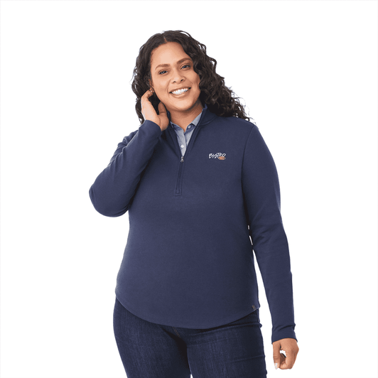 A woman wearing a navy quarter zip jacket with a logo, featuring long sleeves and a curved hem.