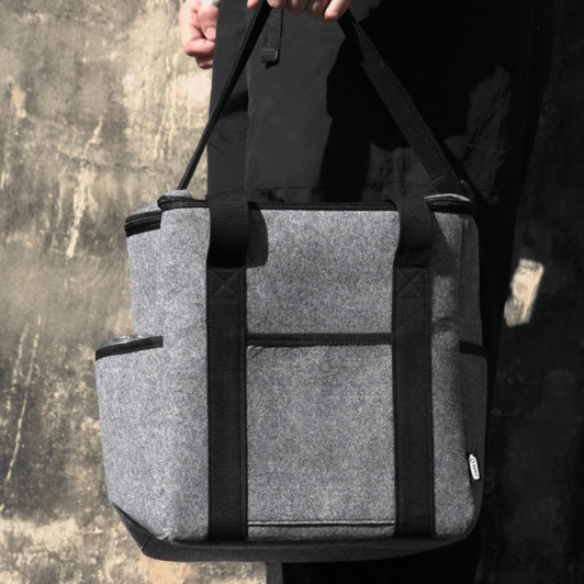 A drink bottle cooler bag in grey felt with black straps, featuring side pockets and a logo.