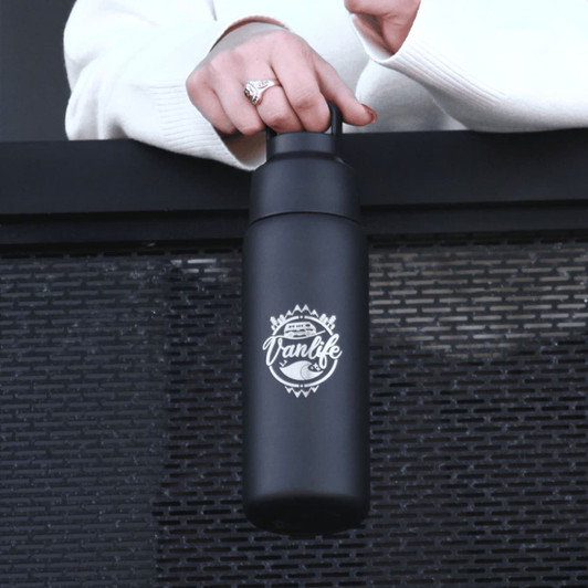 A drink bottle in matte black with a handle, featuring a logo. It has a sleek design suitable for on-the-go use.
