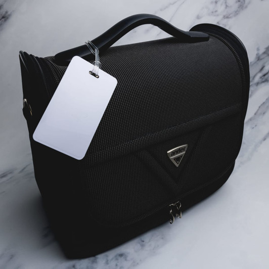 A black luggage tag made of textured material with a handle and a blank tag attached.