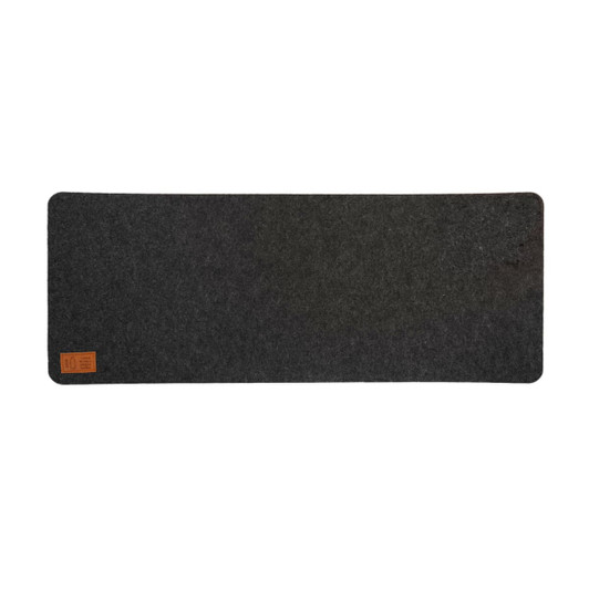 A dark gray desk mat with a felt texture and a small leather label in one corner.