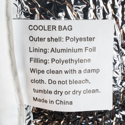A silver cooler bag with a shiny aluminum foil lining and a tag detailing its materials and care instructions.