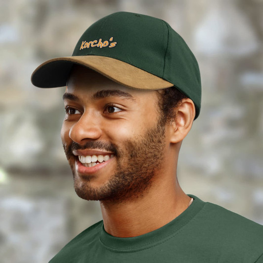 A green peak cap with a brown visor featuring the embroidered text "Korcho's."