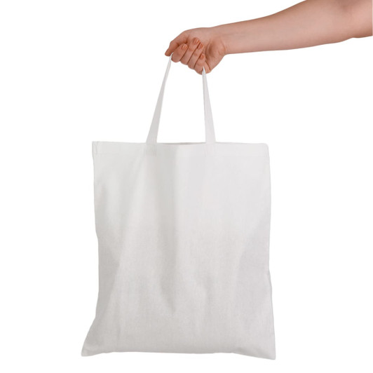 A white cotton tote bag with short handles is held by a hand. The bag features a simple design and a blank surface.