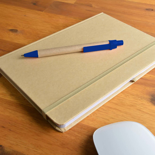 A natural-colored notebook with an elastic band lies on a wooden surface, accompanied by a blue and kraft pen.