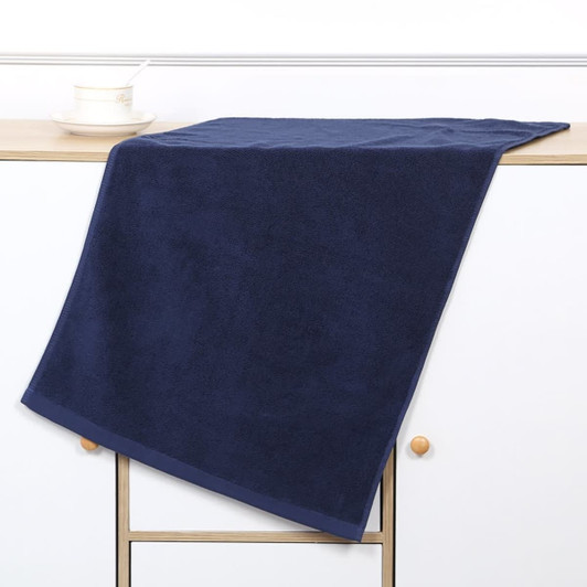 A navy gym towel rests on a wooden surface, showcasing a soft texture and hemmed edges. It features a logo.