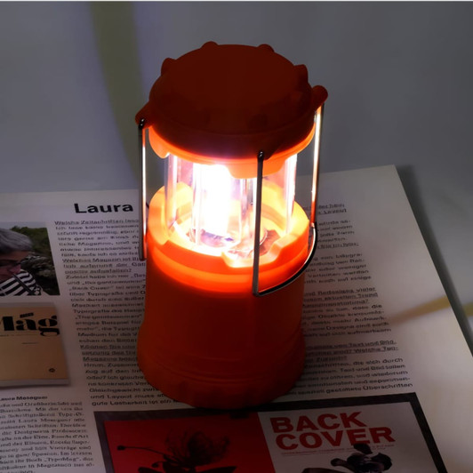 An orange lantern with a transparent casing, emitting light, placed on top of a magazine.