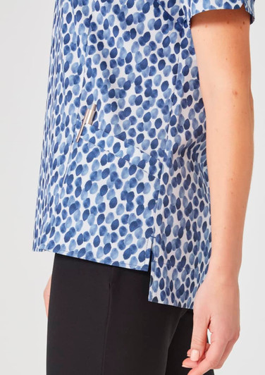 A women's tunic in a blue stardust print features a pocket and side slits, paired with black trousers.