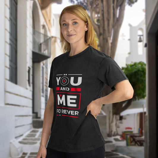 A black unisex T-shirt featuring bold text and a logo, displayed by a model in a scenic outdoor setting.