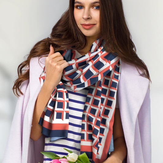 A woman wearing a patterned Berlin scarf in coral, navy, and cream, holding a bouquet of flowers.