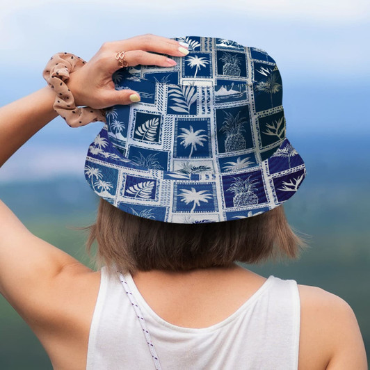 A blue and white patterned bucket hat featuring palm prints, viewed from behind on a person in a sleeveless top.