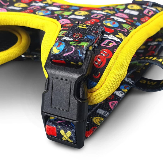 A pet harness in black with bright, colourful patterns and yellow accents, featuring a plastic buckle.