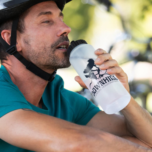 A drink bottle with a black cap, featuring a logo, is held by a man wearing a helmet and teal shirt.