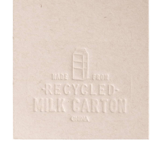 A cream-colored bookmark designed to resemble a milk carton, featuring embossed details and a logo.