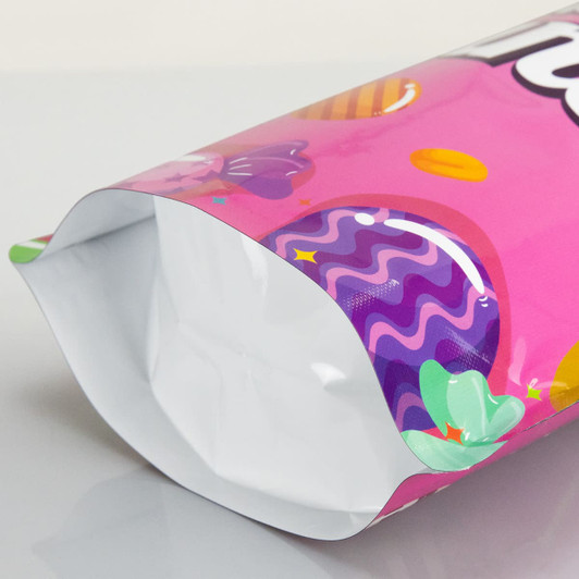 A medium-sized, pink foil stand-up pouch featuring colourful patterns and a glossy finish, with a white interior.