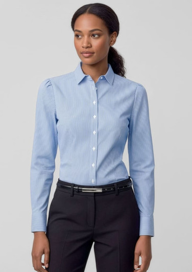 A women's long sleeve button-up shirt in light blue, featuring a collar and fitted design, paired with dark trousers.