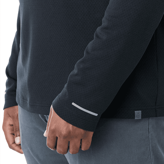 A close-up of a dark navy quarter-zip jacket featuring a reflective detail on the sleeve and a subtle logo.