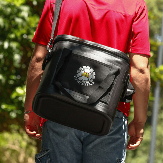 A black cooler bag with a shoulder strap and a logo, carried by a person wearing a red shirt.
