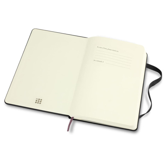 An open Moleskine 2026 planner with blank white pages and a black cover, featuring a ribbon bookmark and a branding logo.