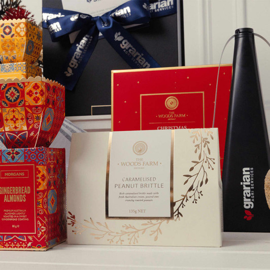 A gift set featuring colourful boxes of gingerbread almonds, a card, and a sleek black bottle with a logo.