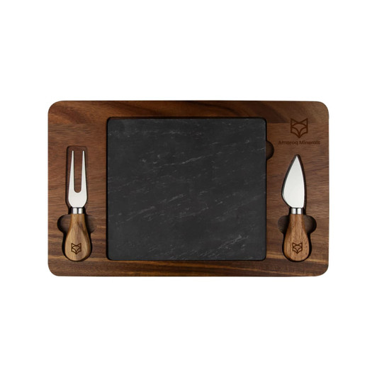 A slate cheeseboard with a wooden border and two cheese knives, featuring a logo. The board has a rectangular shape.