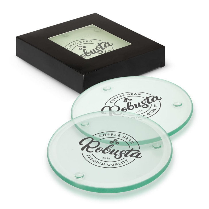 A set of four round glass coasters in light green, displayed in a black box with a logo.