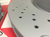 Close-up of Zimmermann perforated brake disc showing cross-drilled holes and silver Z-Coat finish.