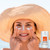 This is a lifestyle image of a woman with dots of Face Sunscreen on her skin with a hat for additional sun protection.