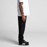 Straight elastic pants in black, displayed on a model from the side, paired with black sneakers and a white t-shirt.