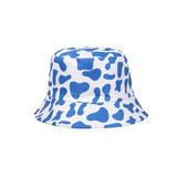 A blue and white bucket hat featuring a cow print pattern, with a branded logo on the side.