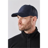 A navy trucker cap featuring a mesh back and a solid front panel, shown on a model against a neutral background.