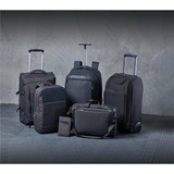 A collection of black bags, including backpacks, a wheeled suitcase, and a messenger bag, with a sleek design.