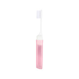 A transparent pink foldable handle toothbrush with a white bristle head, encased in a matching transparent holder.