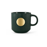 A dark green ceramic mug featuring a ribbed texture and a bronze medal emblem on the front.