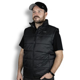 A man wearing a black puffer vest, featuring a zip front and a collar, with a logo on the upper left. A man wearing a black puffer vest, featuring a zip front and a collar, with a logo on the upper left.