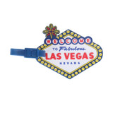 A custom-shaped PVC luggage tag featuring a colourful design with a welcome message and a blue attachment.