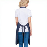 A navy denim full bib apron with a neck strap, featuring a back tie and worn over a white polo shirt.