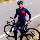 Men's sublimated cycling tights in navy with red and blue graphics, worn by a cyclist beside a bicycle on a road.