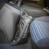 A black Car Tidy bag hanging from a car's centre console, positioned next to a striped seat.