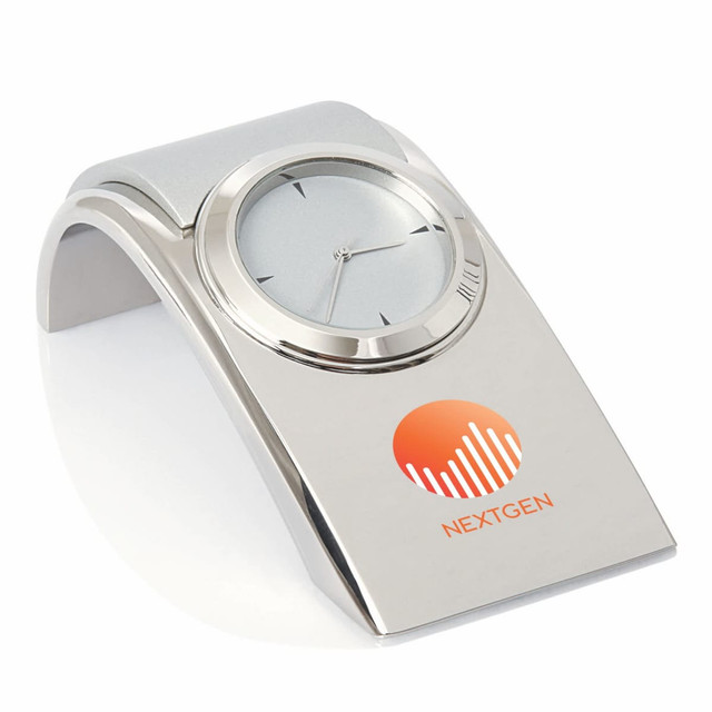 A sleek silver desk clock with a curved base and a logo, featuring a minimalist design.