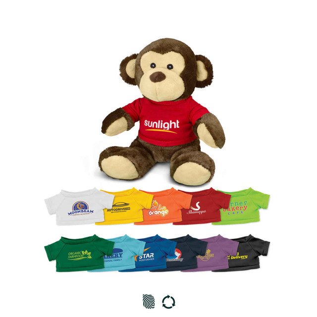 A brown monkey plush toy wearing a red shirt with branding, surrounded by various small shirts in different colours.