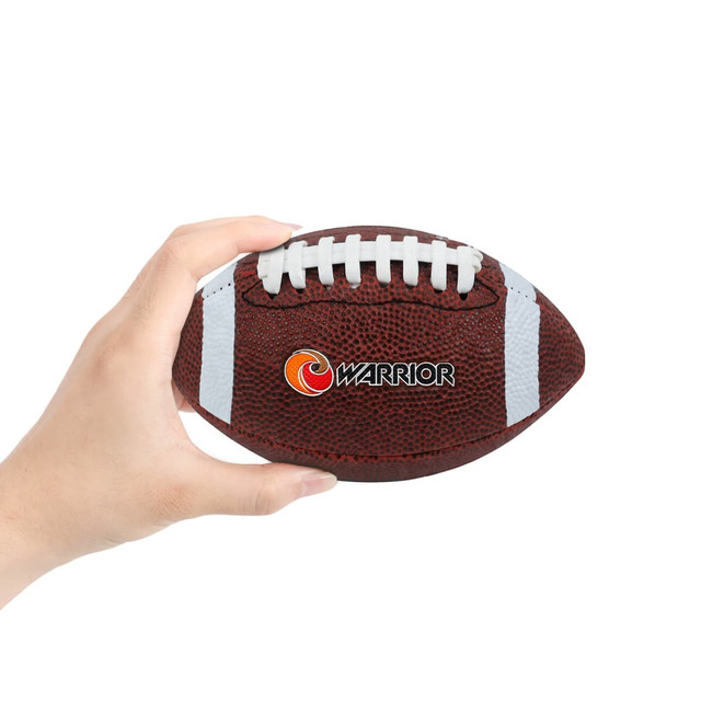 A hand holding a small brown promotional American football with white stripes and a logo.