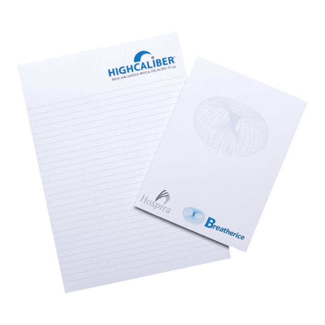 A notepad featuring lined pages, with a logo on the top and a smaller pad beside it, on a wooden surface.
