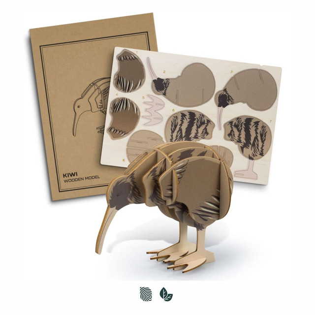 A wooden kiwi model in natural shades, with assembly pieces and a design template in the background. Contains a logo.